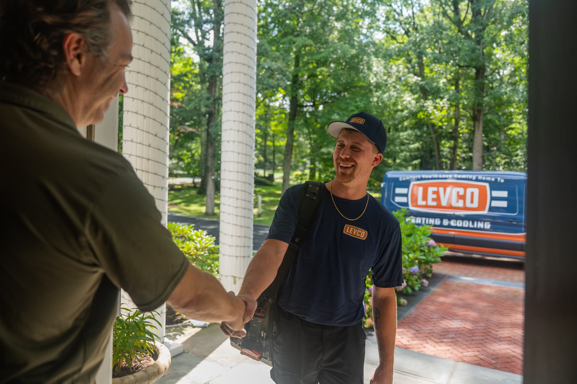 Levco technician greeting a homeowner with a service van in the driveway