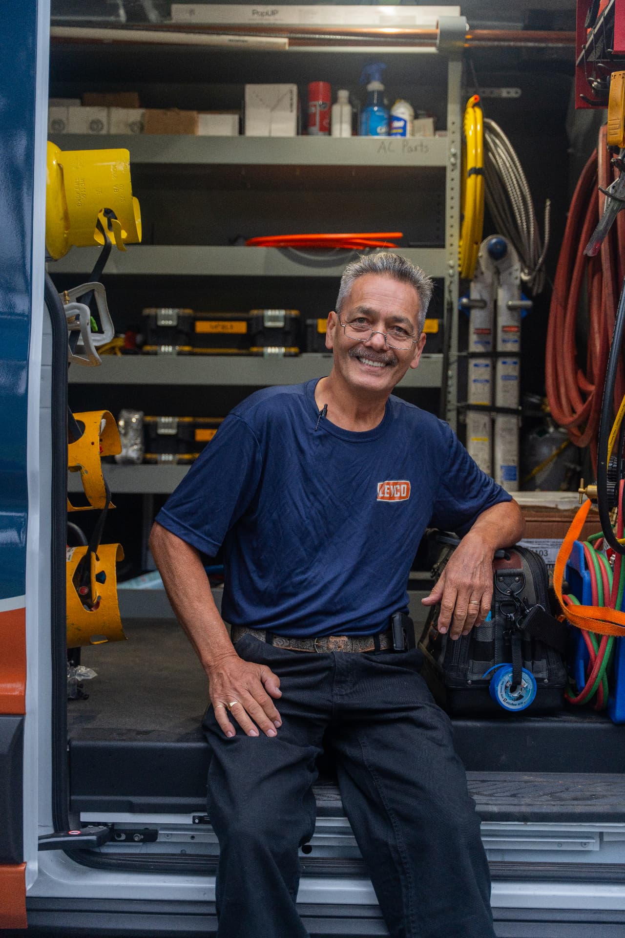 Smiling Levco technician seated in a fully stocked service van