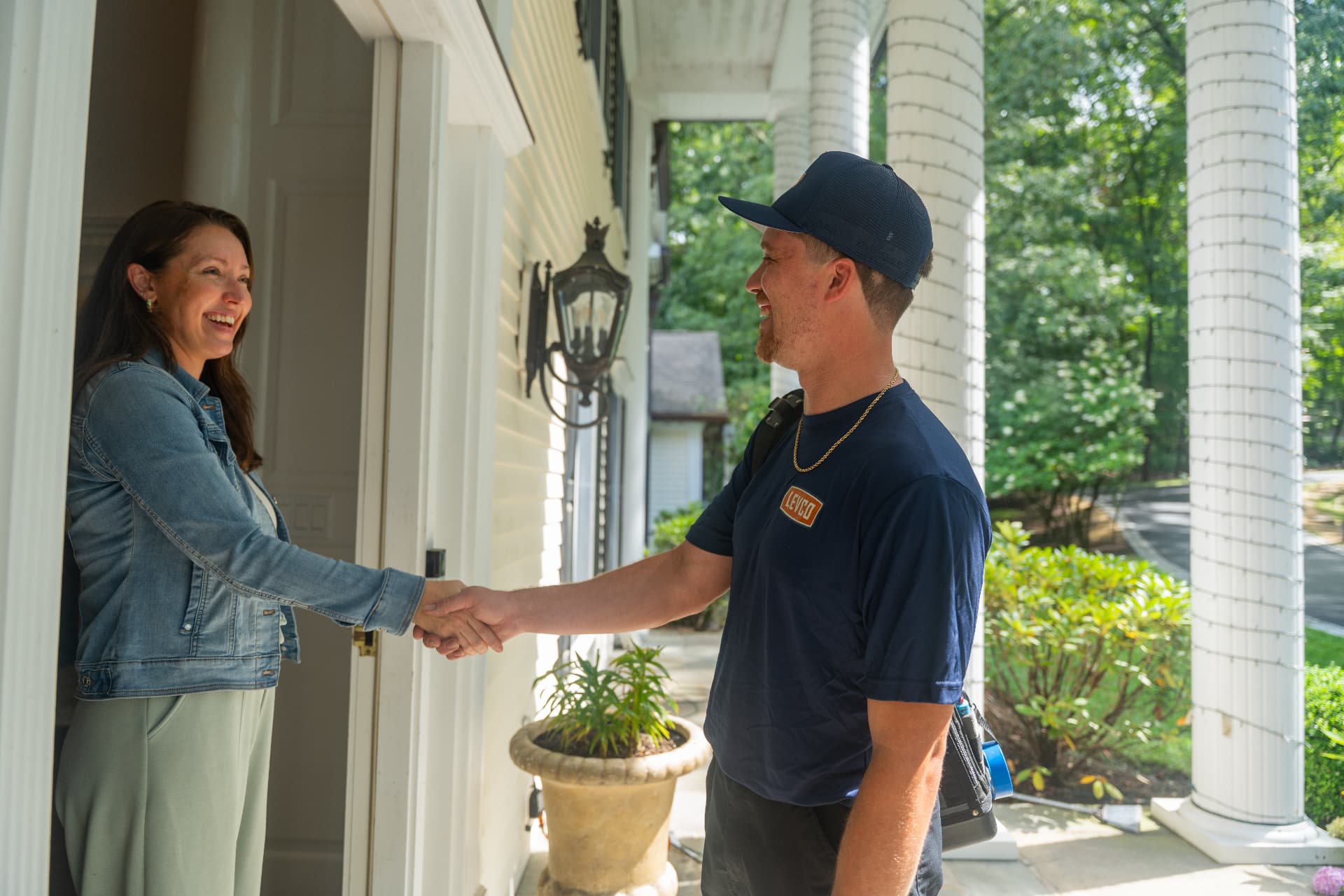 Levco team member shaking hands with a smiling homeowner on her front porch