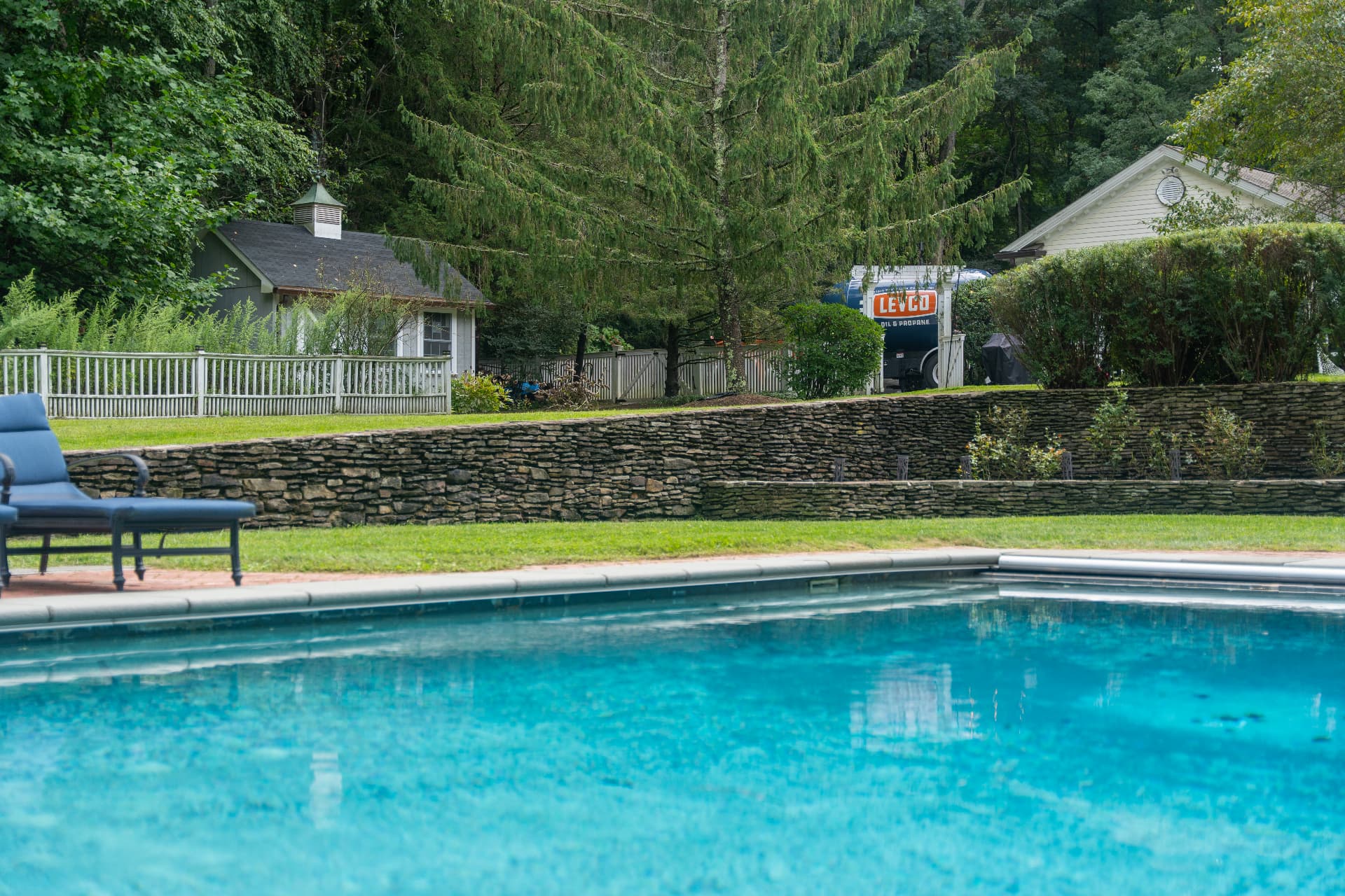 Levco technician inspecting an outdoor pool heater beside a Connecticut pool