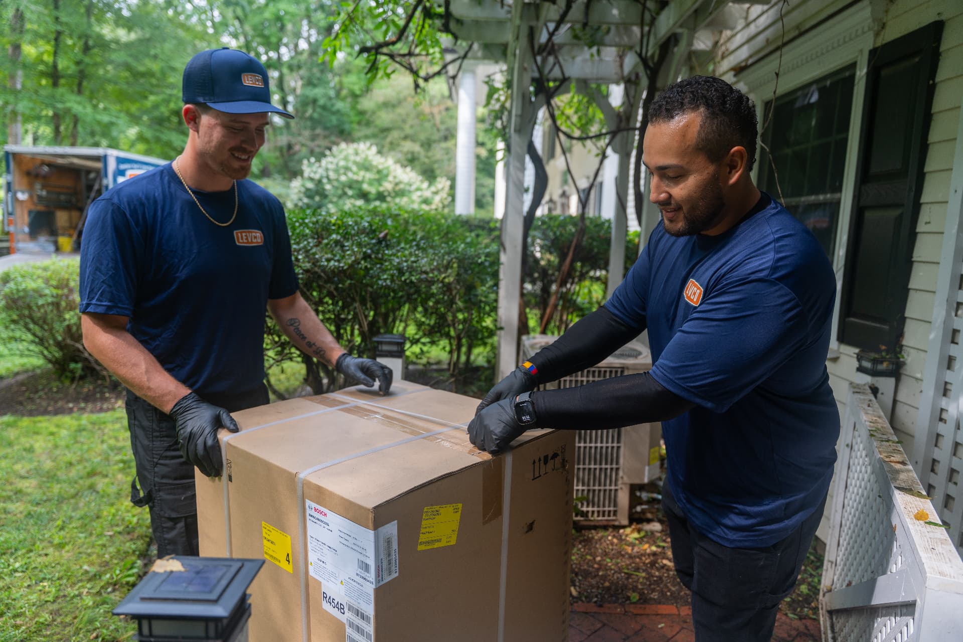 Levco technicians unpacking a new heating and cooling system beside the unit it replaces