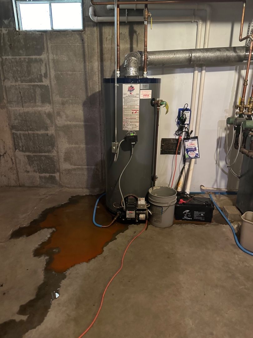 Older tank water heater leaking onto a basement floor before replacement