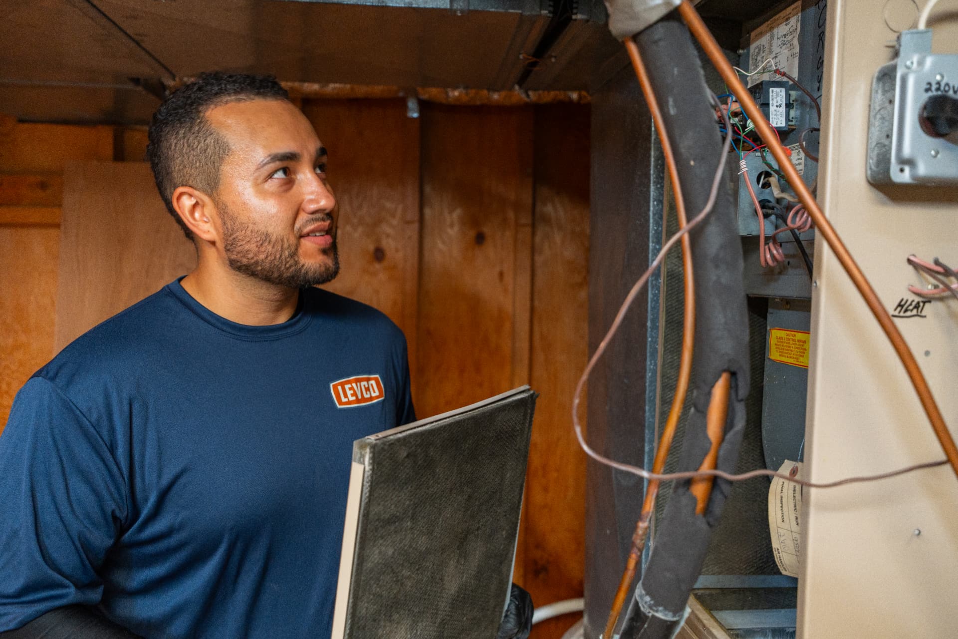 Levco technician inspecting a furnace filter and internal controls during an annual tune-up