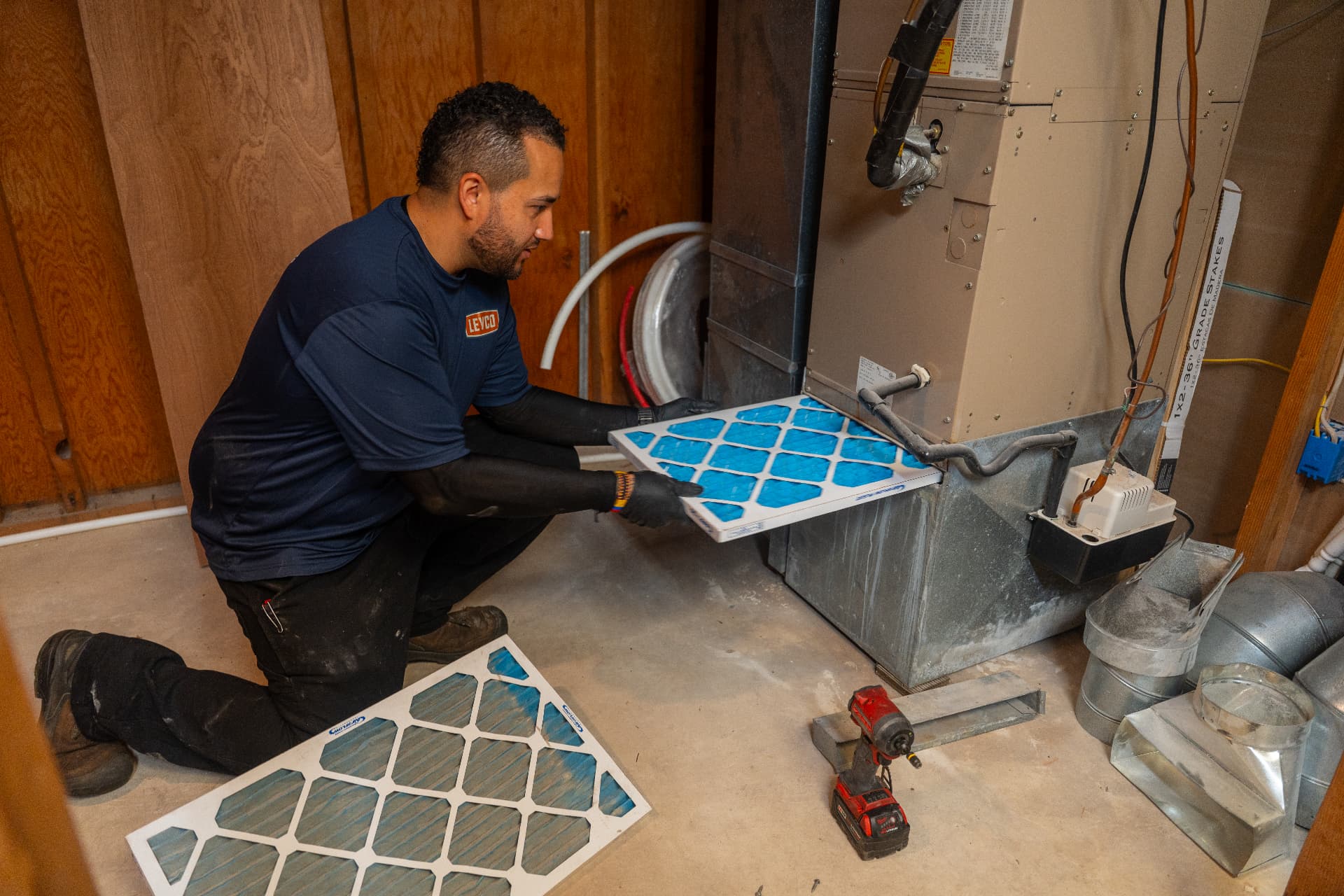 Levco technician replacing an air filter in a home heating and cooling system