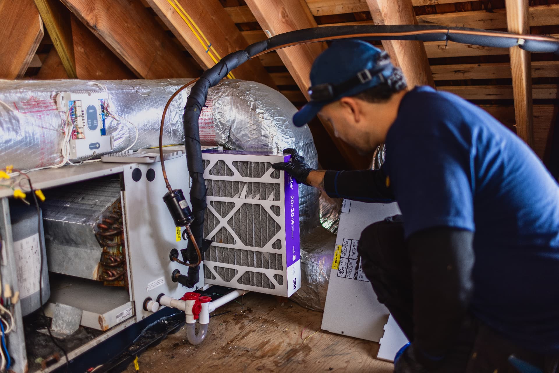 Levco technician replacing a whole-home air filter at an attic air handler