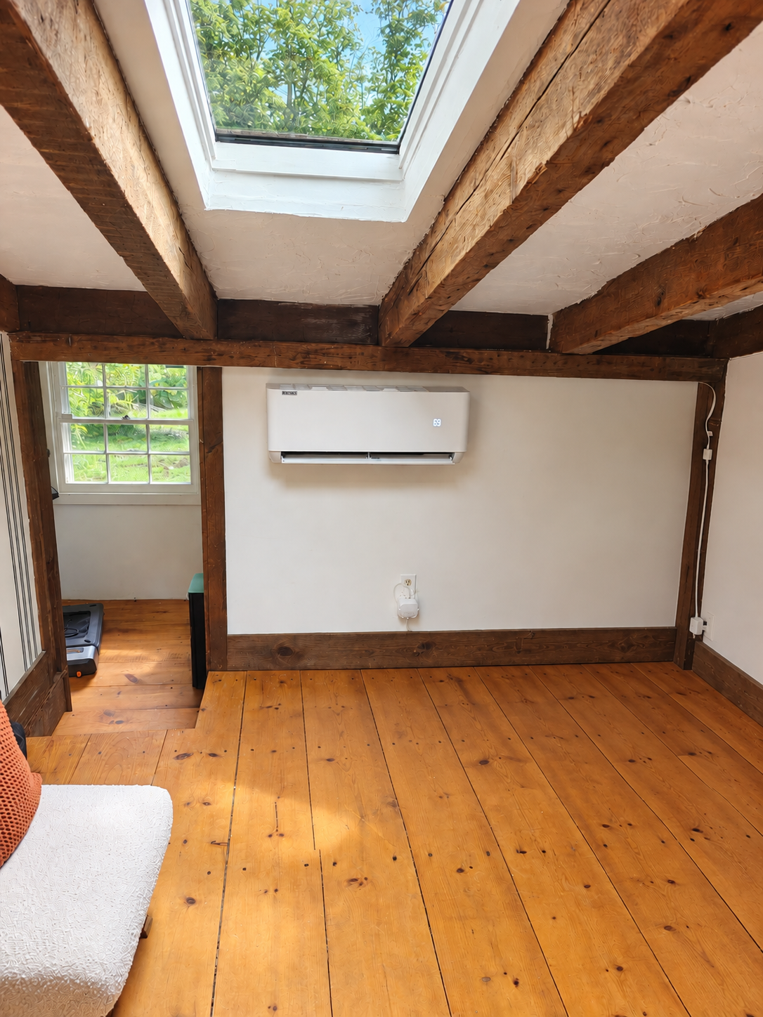 Ductless mini-split providing comfort in a finished attic room with exposed beams