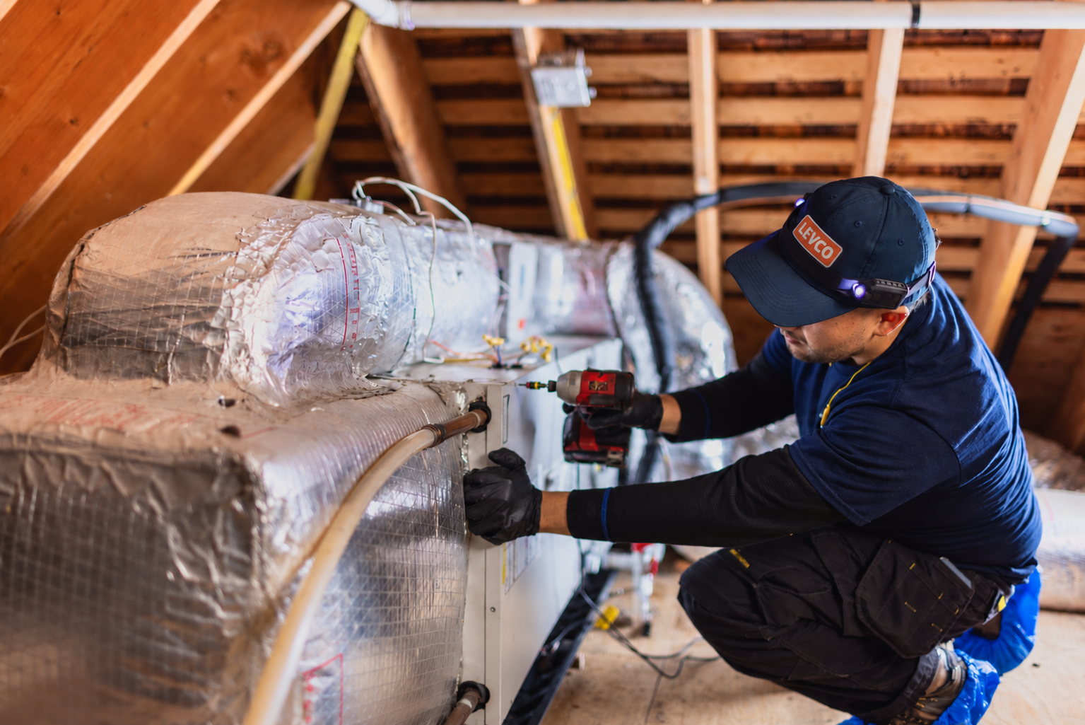 Technician installing and checking cooling equipment in a Connecticut attic